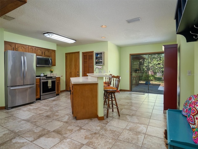 113 Myrtlewood Point Rd, East Palatka, FL 32131 - kitchen featuring stainless steel appliances, a textured ceiling, light countertops, a kitchen breakfast bar, and baseboards