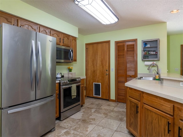 113 Myrtlewood Point Rd, East Palatka, FL 32131 - kitchen featuring stainless steel appliances, a sink, light countertops, a textured ceiling, and brown cabinets