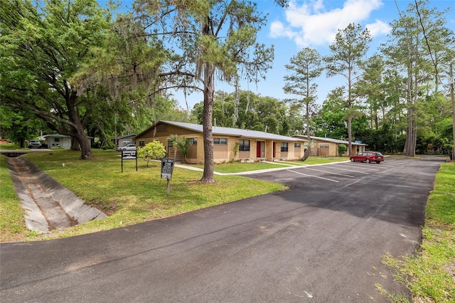 915 NW 40th Ave, Gainesville, Fl, FL 32605 - view of front facade with uncovered parking, a front lawn, and view of scattered trees