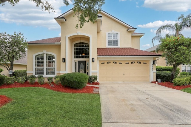 1726 Chatham Village Dr, Fleming Island, FL 32003 - mediterranean / spanish-style home featuring stucco siding, driveway, a front lawn, an attached garage, and roof with shingles
