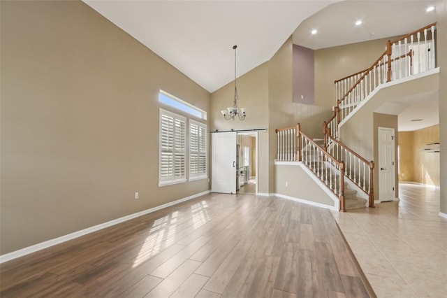 1726 Chatham Village Dr, Fleming Island, FL 32003 - entrance foyer featuring a barn door, high vaulted ceiling, stairs, a chandelier, and baseboards