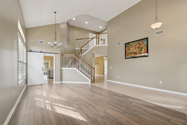 1726 Chatham Village Dr, Fleming Island, FL 32003 - unfurnished living room with a barn door, high vaulted ceiling, stairs, a chandelier, and baseboards