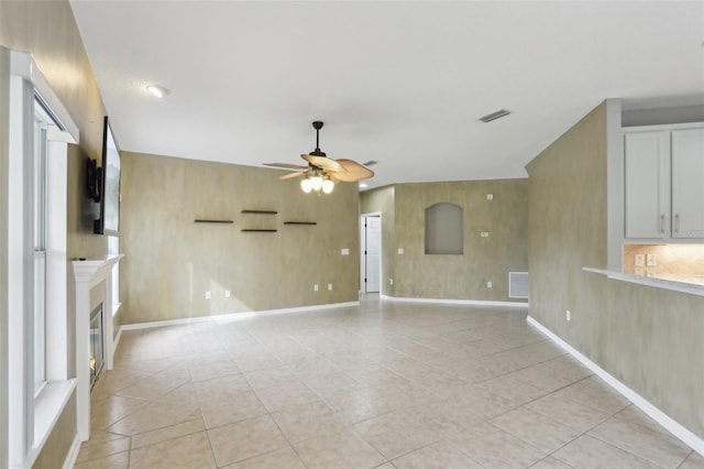 1726 Chatham Village Dr, Fleming Island, FL 32003 - unfurnished living room with a ceiling fan, a glass covered fireplace, light tile patterned flooring, and baseboards