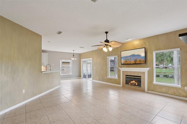 1726 Chatham Village Dr, Fleming Island, FL 32003 - unfurnished living room featuring light tile patterned flooring, a ceiling fan, a glass covered fireplace, baseboards, and a sink