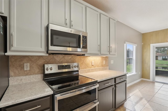 1726 Chatham Village Dr, Fleming Island, FL 32003 - kitchen with stainless steel appliances, decorative backsplash, light tile patterned floors, and baseboards