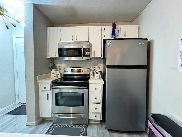4000 SW 23rd St Unit 3-205, Gainesville, FL 32608 - kitchen featuring appliances with stainless steel finishes, light wood-style flooring, white cabinetry, light countertops, and backsplash