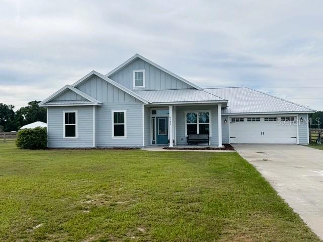 6180 SW 83rd Pl, Trenton, FL 32693 - view of front of property with board and batten siding, driveway, an attached garage, covered porch, and a front lawn