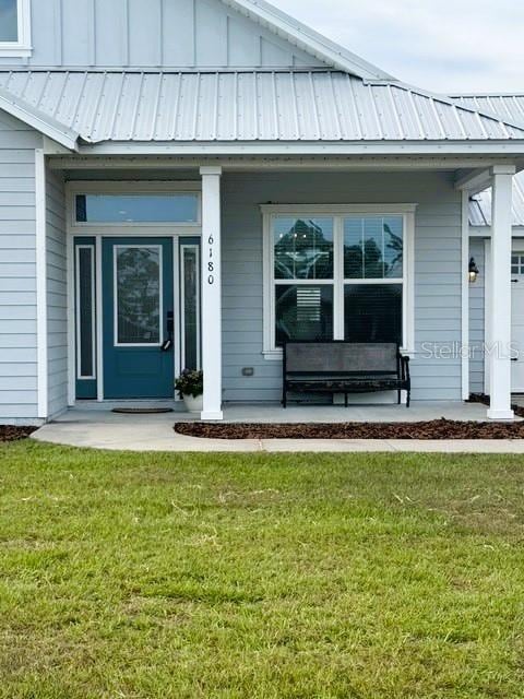 6180 SW 83rd Pl, Trenton, FL 32693 - property entrance with a porch, board and batten siding, a lawn, and metal roof