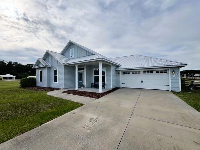 6180 SW 83rd Pl, Trenton, FL 32693 - view of front of house featuring board and batten siding, driveway, a porch, a front yard, and a garage