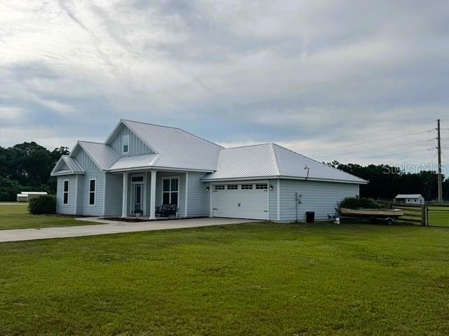 6180 SW 83rd Pl, Trenton, FL 32693 - view of front of home with concrete driveway, a front yard, an attached garage, a porch, and board and batten siding