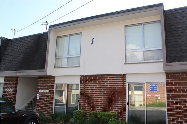 1700 SW 16th Ct Unit J21, Gainesville, FL 32608 - view of front of house with brick siding, a shingled roof, and mansard roof