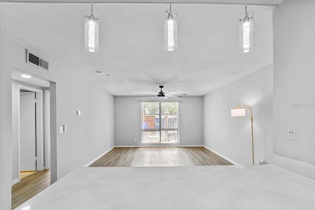 1700 SW 16th Ct Unit J21, Gainesville, FL 32608 - unfurnished room featuring a textured ceiling, ceiling fan, wood finished floors, and baseboards