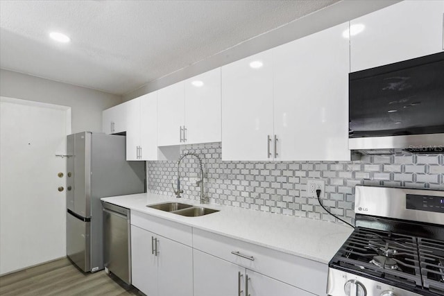 1700 SW 16th Ct Unit J21, Gainesville, FL 32608 - kitchen with appliances with stainless steel finishes, a sink, light countertops, light wood-type flooring, and white cabinetry