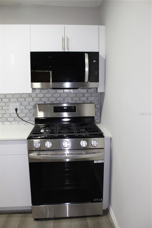 1700 SW 16th Ct Unit J21, Gainesville, FL 32608 - kitchen with stainless steel appliances, light countertops, white cabinets, and decorative backsplash