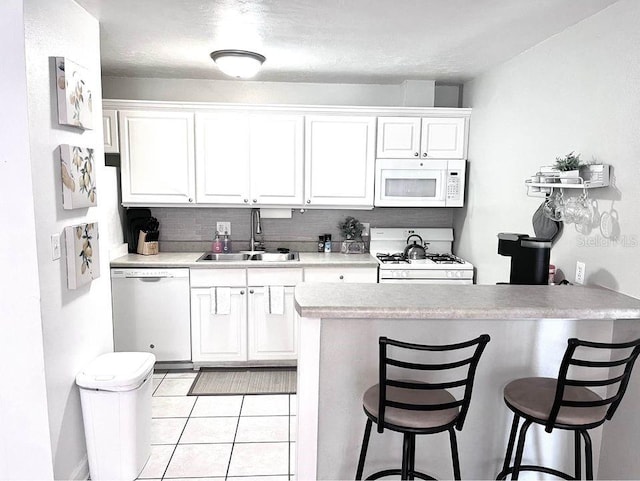 1700 SW 16th Ct Unit D30, Gainesville, FL 32608 - kitchen featuring white appliances, a sink, white cabinetry, and a breakfast bar