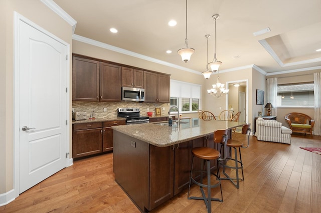 2638 SW 118th Ter, Gainesville, FL 32608 - kitchen with appliances with stainless steel finishes, a sink, light wood-style flooring, light stone countertops, and crown molding