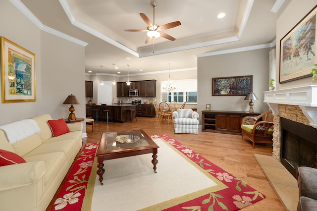 2638 SW 118th Ter, Gainesville, FL 32608 - living room with a raised ceiling, light wood-style floors, a fireplace, a ceiling fan, and a chandelier