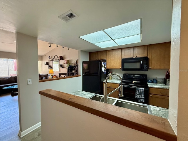 2058 SW 35th Pl Unit H47, Gainesville, FL 32608 - kitchen with black appliances, a skylight, a sink, light countertops, and baseboards