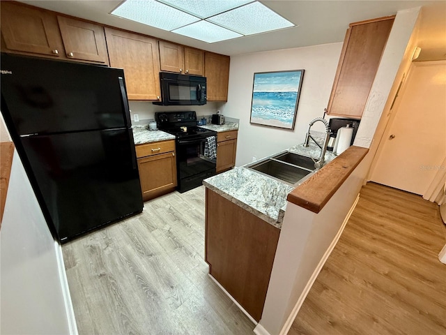 2058 SW 35th Pl Unit H47, Gainesville, FL 32608 - kitchen featuring black appliances, a sink, light wood-type flooring, and a peninsula