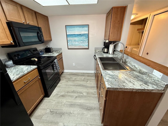 2058 SW 35th Pl Unit H47, Gainesville, FL 32608 - kitchen featuring black appliances, a sink, brown cabinets, light wood finished floors, and a peninsula