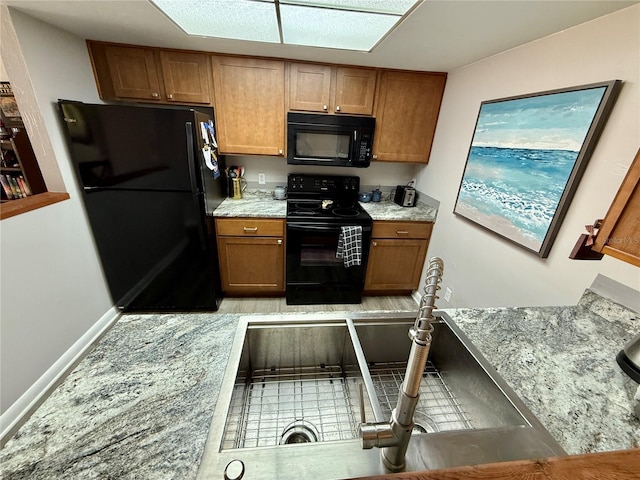 2058 SW 35th Pl Unit H47, Gainesville, FL 32608 - kitchen featuring black appliances, brown cabinets, light stone countertops, and baseboards
