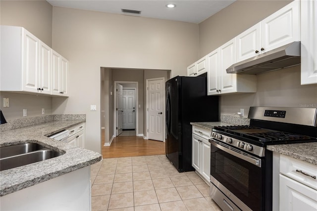 8103 SW 71st Ln, Gainesville, FL 32608 - kitchen with stainless steel range with gas stovetop, under cabinet range hood, light tile patterned flooring, a sink, and white cabinets
