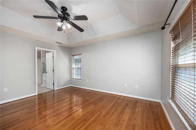 8103 SW 71st Ln, Gainesville, FL 32608 - unfurnished bedroom featuring a tray ceiling, wood finished floors, baseboards, and ensuite bathroom