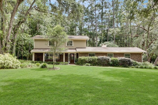 11011 NW 12th Pl, Gainesville, FL 32606 - traditional-style home with a front lawn, brick siding, and a chimney