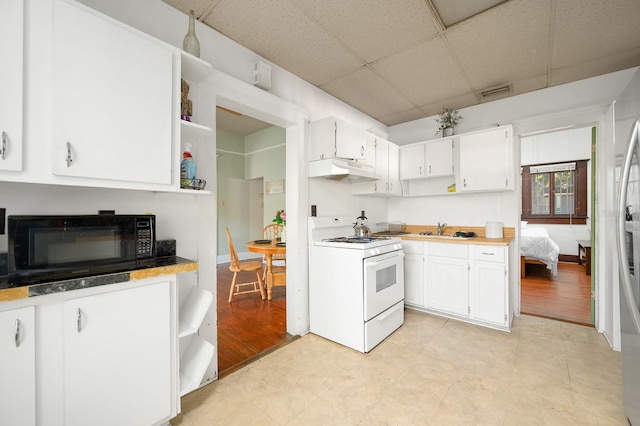 119 NW 7th Ter, Gainesville, FL 32601 - kitchen featuring white range with gas cooktop, black microwave, under cabinet range hood, a paneled ceiling, and open shelves