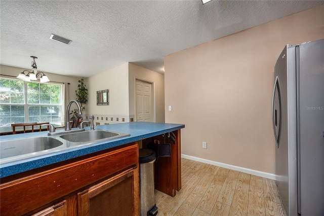 1841 SE 245th St, Hawthorne, FL 32640 - kitchen featuring freestanding refrigerator, a sink, light wood finished floors, a chandelier, and a textured ceiling