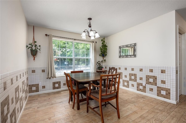1841 SE 245th St, Hawthorne, FL 32640 - dining space with light wood finished floors, a chandelier, a wainscoted wall, and tile walls