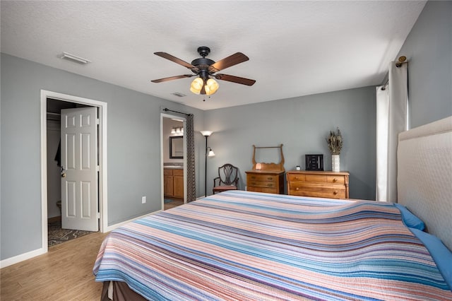 1841 SE 245th St, Hawthorne, FL 32640 - bedroom featuring light wood-type flooring, ensuite bathroom, ceiling fan, baseboards, and a walk in closet