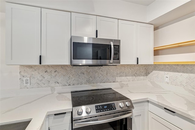 2735 SW 35th Pl Unit 1905, Gainesville, FL 32608 - kitchen featuring appliances with stainless steel finishes, open shelves, white cabinetry, backsplash, and light stone counters