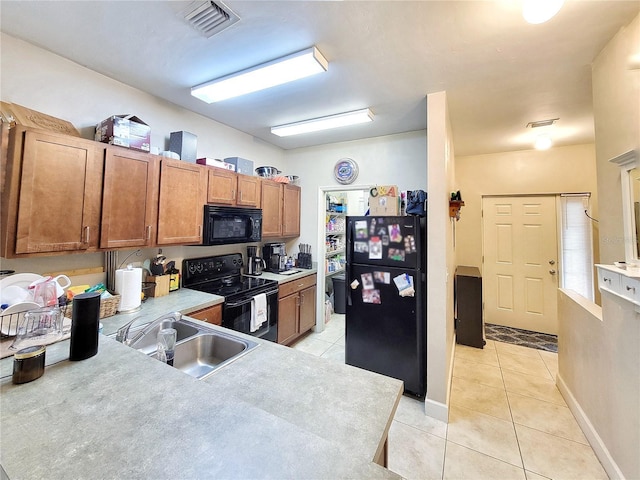 2951 SW 35th Pl Unit 148, Gainesville, FL 32608 - kitchen with black appliances, a sink, light tile patterned flooring, and brown cabinets