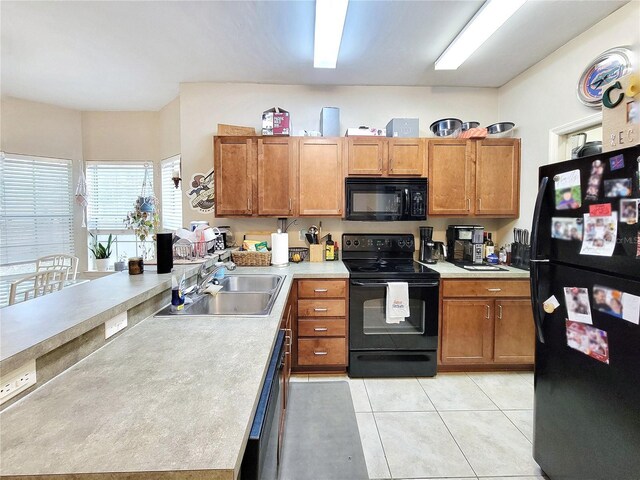 2951 SW 35th Pl Unit 148, Gainesville, FL 32608 - kitchen featuring black appliances, a sink, a peninsula, light countertops, and brown cabinetry