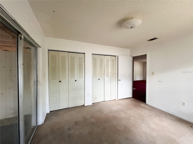 6226 SW 10th Pl, Gainesville, FL 32607 - unfurnished bedroom with multiple closets, carpet floors, a textured ceiling, and baseboards