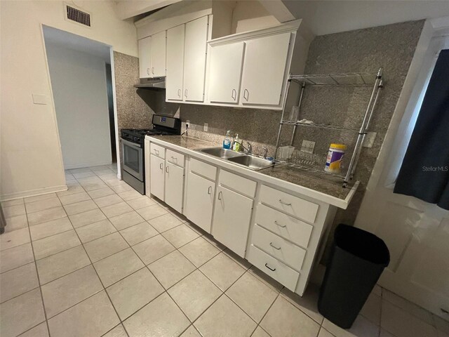 3008 NE 11th Dr, Gainesville, FL 32609 - kitchen with stainless steel gas range, under cabinet range hood, a sink, light tile patterned flooring, and white cabinetry