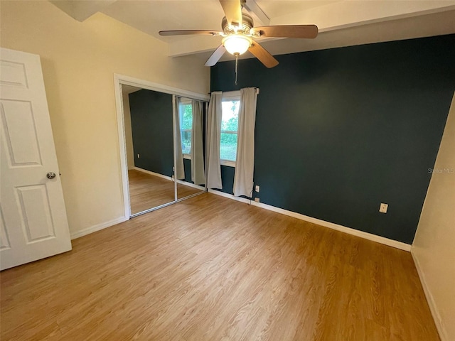 3008 NE 11th Dr, Gainesville, FL 32609 - unfurnished bedroom with light wood-style floors, baseboards, ceiling fan, beam ceiling, and a closet