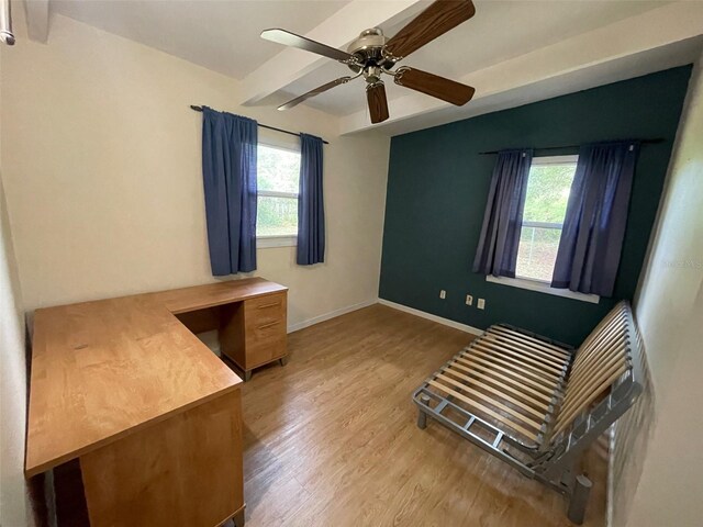 3008 NE 11th Dr, Gainesville, FL 32609 - unfurnished bedroom featuring wood finished floors, baseboards, beamed ceiling, a desk, and a ceiling fan