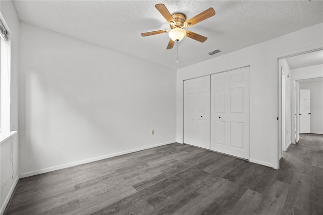 3026 NW 28th Cir, Gainesville, FL 32605 - unfurnished bedroom featuring a textured ceiling, dark wood-style floors, a closet, and baseboards