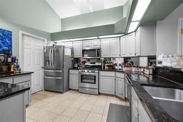 5434 SW 91st Ter, Gainesville, FL 32608 - kitchen with appliances with stainless steel finishes, light tile patterned flooring, high vaulted ceiling, dark stone countertops, and a sink