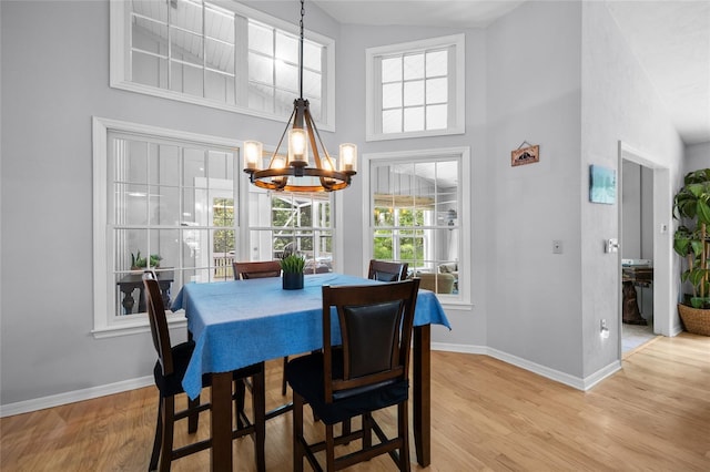5434 SW 91st Ter, Gainesville, FL 32608 - dining space with a high ceiling, a chandelier, baseboards, and light wood finished floors