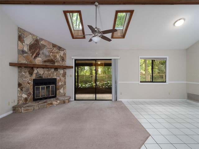 3703 NW 107th Ter, Gainesville, FL 32606 - unfurnished living room featuring a skylight, vaulted ceiling, a stone fireplace, ceiling fan, and carpet