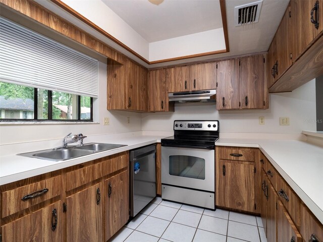 3703 NW 107th Ter, Gainesville, FL 32606 - kitchen featuring appliances with stainless steel finishes, a sink, under cabinet range hood, light tile patterned flooring, and brown cabinetry