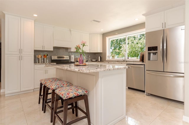 18101 Boy Scout Rd, Odessa, FL 33556 - kitchen featuring stainless steel appliances, light tile patterned flooring, tasteful backsplash, a kitchen island, and white cabinetry