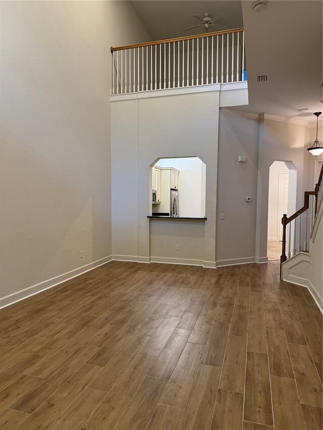1848 NW 34th St Unit 23, Gainesville, FL 32605 - unfurnished living room featuring arched walkways, a ceiling fan, wood finished floors, stairway, and a towering ceiling
