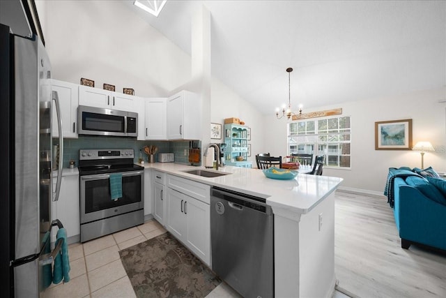 10000 SW 52nd Ave Unit 120, Gainesville, FL 32608 - kitchen with stainless steel appliances, a sink, a peninsula, a chandelier, and tasteful backsplash