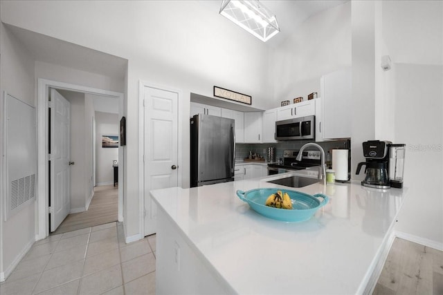 10000 SW 52nd Ave Unit 120, Gainesville, FL 32608 - kitchen with stainless steel appliances, a peninsula, a sink, light countertops, and decorative backsplash