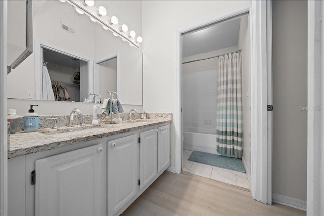 10000 SW 52nd Ave Unit 120, Gainesville, FL 32608 - bathroom featuring double vanity, wood finished floors, shower / bathtub combination with curtain, baseboards, and a spacious closet