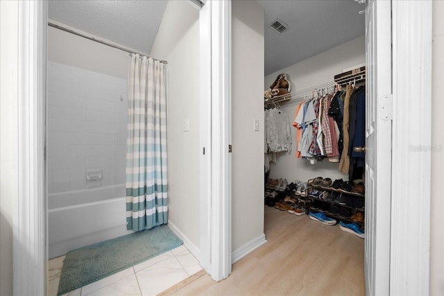 10000 SW 52nd Ave Unit 120, Gainesville, FL 32608 - full bathroom featuring shower / bathtub combination with curtain, a spacious closet, and wood finished floors